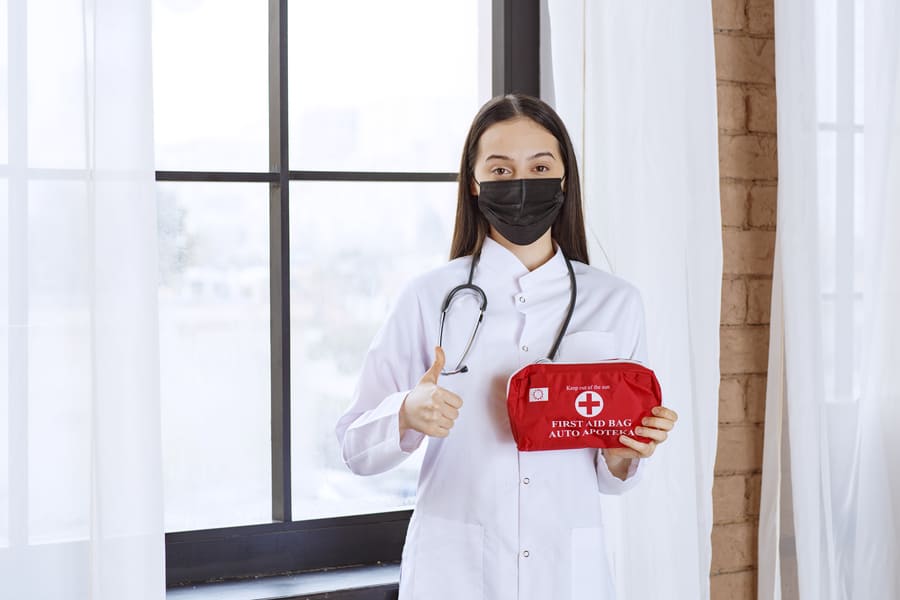 doctor-with-stethoscope-black-mask-holding-red-first-aid-kit-showing-thumb-up (1).jpeg
